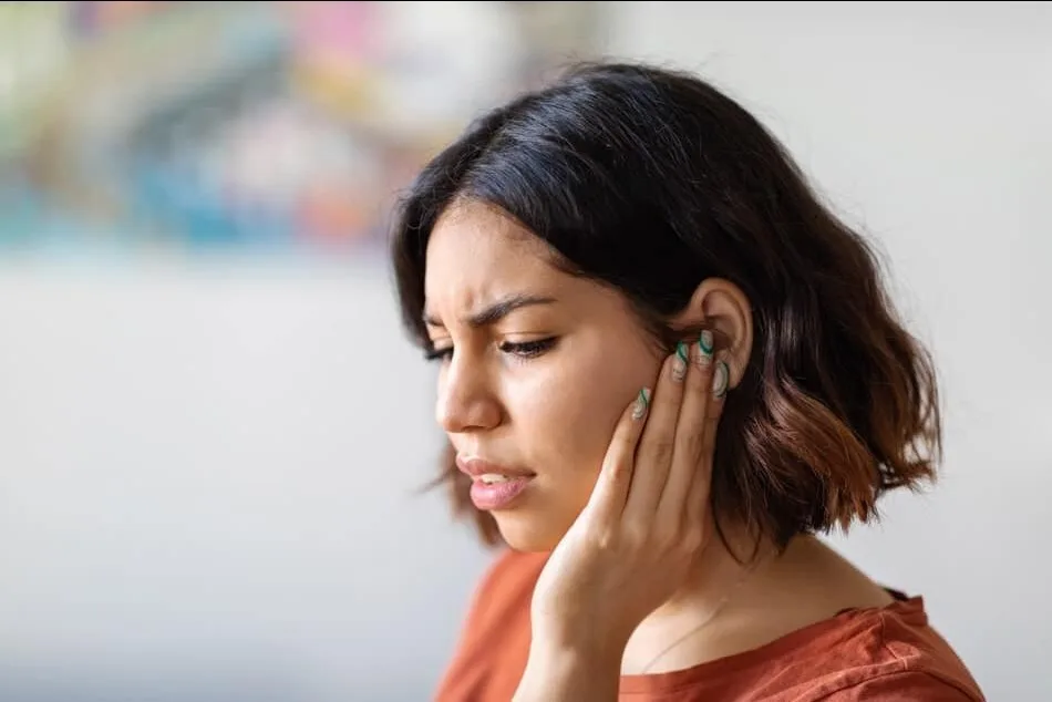 An adult touching their jaw due to early TMD discomfort